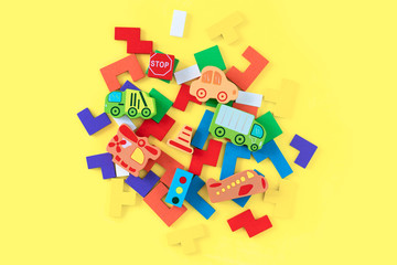 Obraz premium Colorful developing wooden blocks and handmade cars on yellow background. Natural, eco-friendly wooden toys for children. Top view. Flat lay. Copy space.