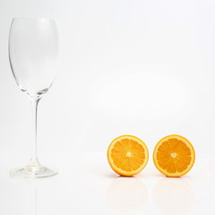 slices of an orange and an empty glass on a white background.