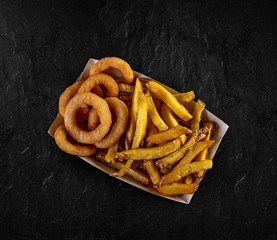 Onion rings and french fries on dark