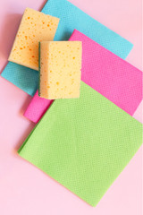 Cleaning concept A set of cleaning tools, rags, sponges, brushes, hands in rubber gloves on a light pink background, top view, flat lay, close-up