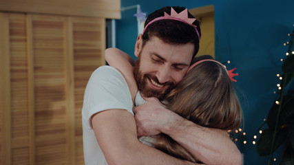 Adorable family home portrait. Closeup happy father and daughter hugging together and smiling of happiness in the room. Daddy and little girl dressed for fancy costume party.