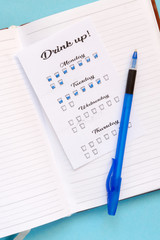 Water tracker, a womans hand notes the number of drinking glasses of water in the habits tracker, the idea of a healthy lifestyle and metabolism