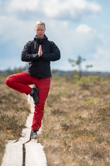 Young Woman practicing Yoga Outdoor in national park with wildlife clothing in wide open landscape background - Horizontal photograph.