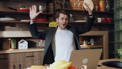 Attractive joyful man dancing excitedly his desk in kitchen. Young attractive Handsome business man funny dancing at home. Happy young positive businessman doing victory dance, successful achievement