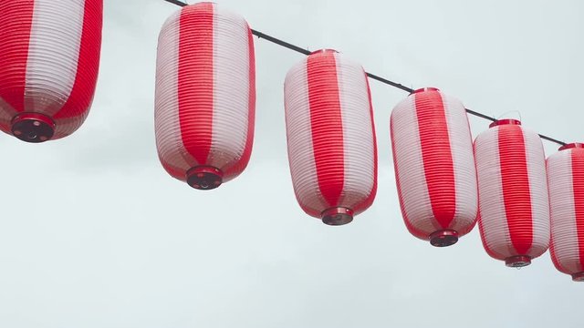 Paper red-white japanese lanterns Chochin hanging on cloudy sky background