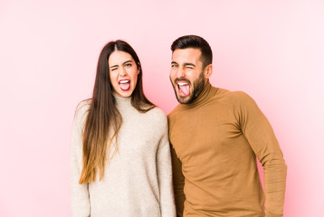 Young caucasian couple isolated funny and friendly sticking out tongue.