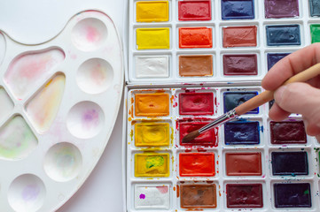 the human hand lowers the brush in watercolors. Art school. Close up.