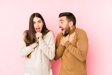 Young caucasian couple isolated praying for luck, amazed and opening mouth looking to front.