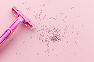 women's shaving machine in pink and hair on a pink background. The concept of women's shaving.