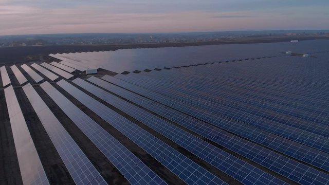 Aerial drone view into large solar panels at a solar farm at sunset. Solar cell power plants. footage video 4k.