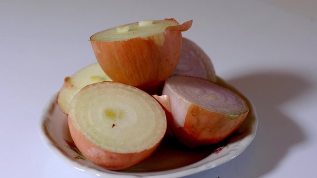 Obraz z ruchomej kamery przekrojonej cebuli położonej na talerzu na jasnym tle 