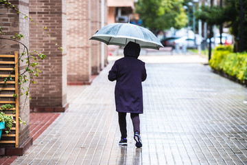 A lonely person walks a rainy day covering himself with an umbrella from bad weather.
