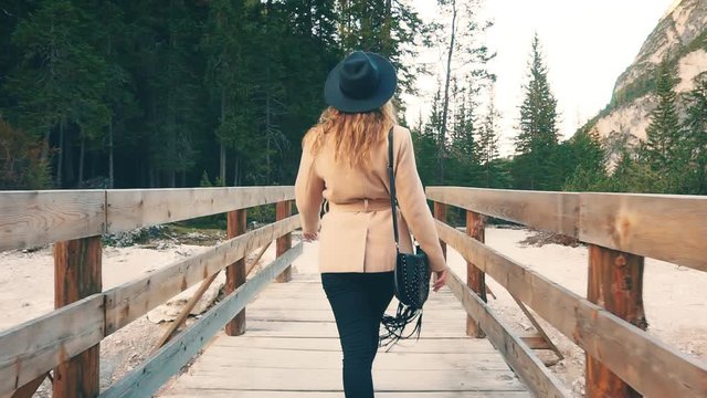 soft colors light, delicate shades beige coat. slender female woman blond wavy hair, young woman explores winter forest, wooden walkways lead to secret paths, trip Italy nature reserves Alp Braies