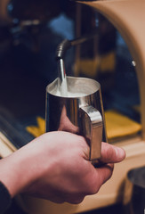 Hand with a pitcher. Whipping milk. Barista