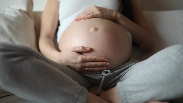 Close-up of the pregnant woman's belly with baby kicks while mother stroking and touching belly with her hand