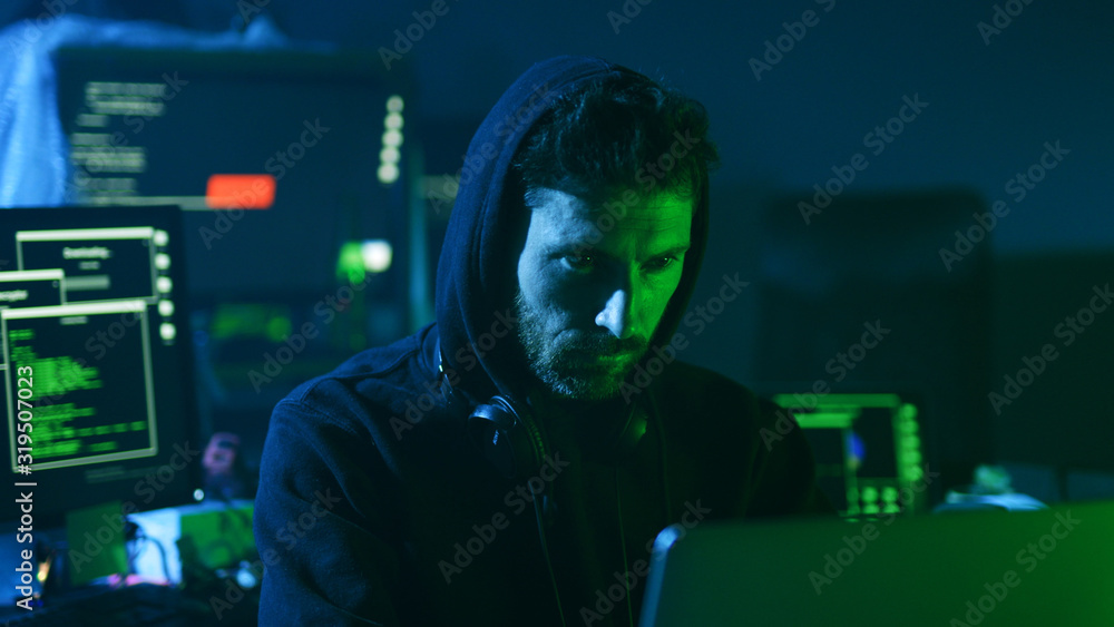 Poster close-up of experienced computer hacker at work. portrait of concentrated young man looking at inter
