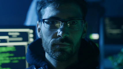 Portrait of handsome smart man in glasses working on computer looking at camera. Close-up of IT developer coding technologies in the studio.