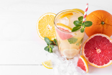 Summer refreshing lemonade with mint on a light background. A glass of citrus cocktail in a light key. Close-up. Summer Vitamin cocktail of orange, lemon and grapefruit.