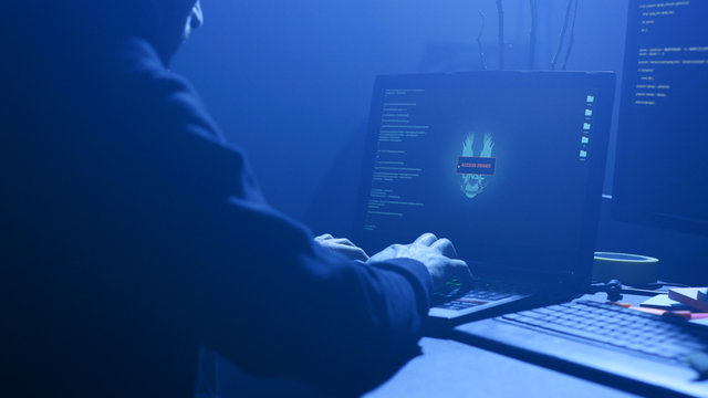 LVIV, UKRAINE - 9 JUNE, 2019: Close-up of computer hacker failing to hack security system on laptop. Anonymous man trying to steal data information from the office. Cyber crime concept.