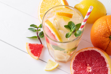 Summer refreshing lemonade with mint on a light background. A glass of citrus cocktail in a light key. Close-up. Summer Vitamin cocktail of orange, lemon and grapefruit.