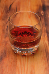 A glass with a dark, cool drink on a wooden Board