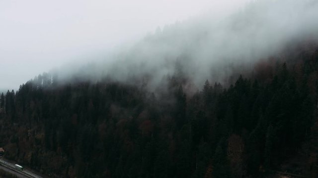 Aerial view. Flying sideways in front of big white clouds up in the mountains.