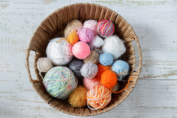Colored threads for knitting in a basket on a wooden background. Knitting concept.