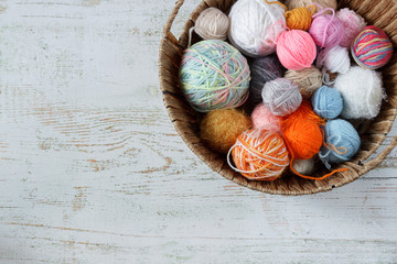 Colored threads for knitting in a basket on a wooden background. Knitting concept.