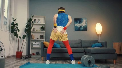 Seductive retro sportsman dancing with funny moves and warming up during training at home. Close-up of young man sexy back moving on mat recording a sports video.