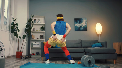Positive funny retro athlete dancing with modern moves warming up before training at home. Sexy guy in stylish sport outfit in good mood preparing for gym.