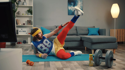 Funny fitness vlogger exercising and training at home. Sportive young man in retro clothes shooting a sports vlog. Motivation and sport concept. - obrazy, fototapety, plakaty