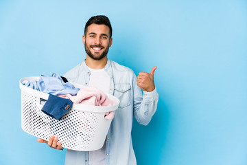 Young handsome man doing laundry isolated smiling and raising thumb up