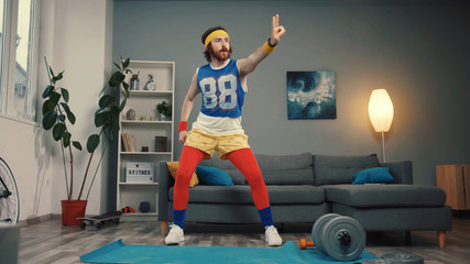 Excited joyful retro sportsman dancing into cool music warming up before hard training at home. - obrazy, fototapety, plakaty
