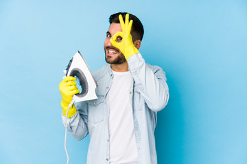 Portrait of young man ironing isolated excited keeping ok gesture on eye.