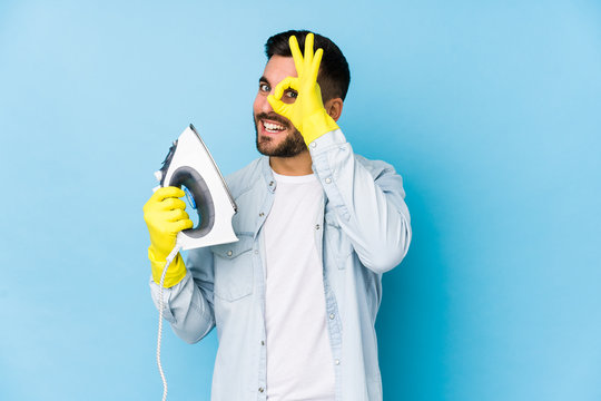 Portrait of young man ironing isolated excited keeping ok gesture on eye.