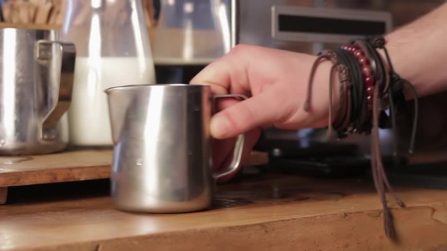 Barista shaking milk for cappuccino. Process of making cappuccino.