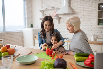 Smiling mom, daughter and grandmother making breakfast.