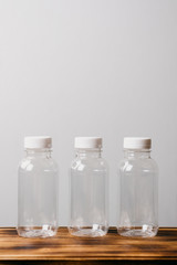 three ecoplastic bottles on a wooden board and gray background, space for text