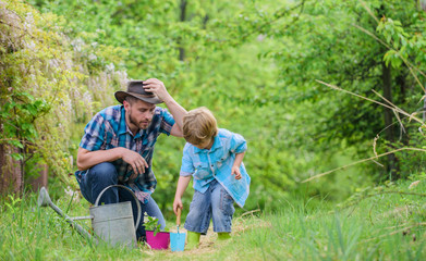 Planting flowers. Dad teaching little son care plants. Little helper in garden. Make planet...