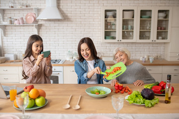 Little girl making video of cooking vegetable salad.