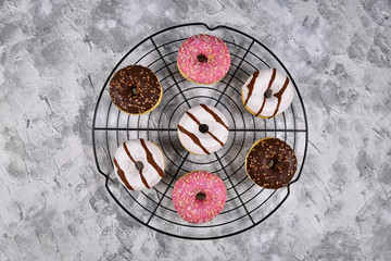 Tasty donuts with different white and brown chocolate and strawberry glazings with sprinkles on cake grid 