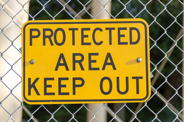 A yellow sign with the words "Protected Area Keep Out."