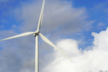 Wind stations. Windmills for electricity production. Wind turbines generating electricity against a cloudy blue sky. Energy saving concept.