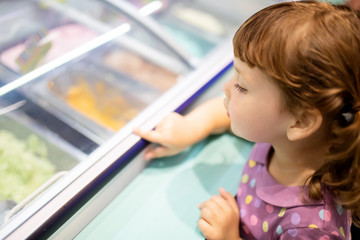Adorable little girl eating ice-cream. Cute kid choose gelato in italian gelateria