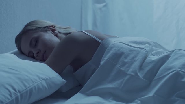 Young woman lying in the bed. Beautiful blond sleeping girl. Morning in the bedroom. Health and rest concept.