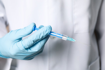 Doctor holds medical syringe of vaccine, injection on brown background. Coronavirus protection....