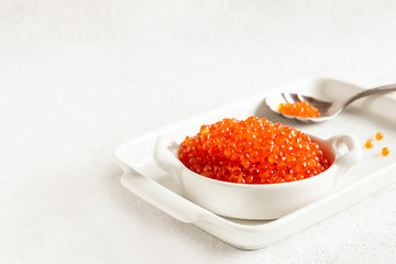 Trout caviar in a white bowl on a white background.
