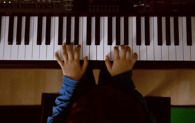 The hands of a child playing the piano