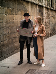 Beautiful and style friends walking with map and camera through the street.