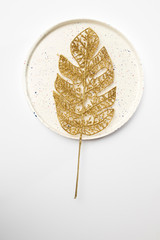 Plastic gold silver branch of exotic plants on white ceramic plate